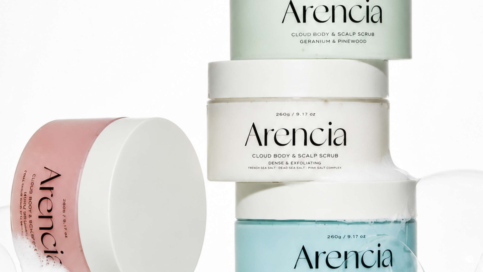 Arencia Cloud Body & Scalp Scrub i flera varianter staplade på kakelhylla. Skonsam kroppsskrubb och skalpskrubb som exfolierar, rengör och ger huden en mjuk och fräsch känsla.