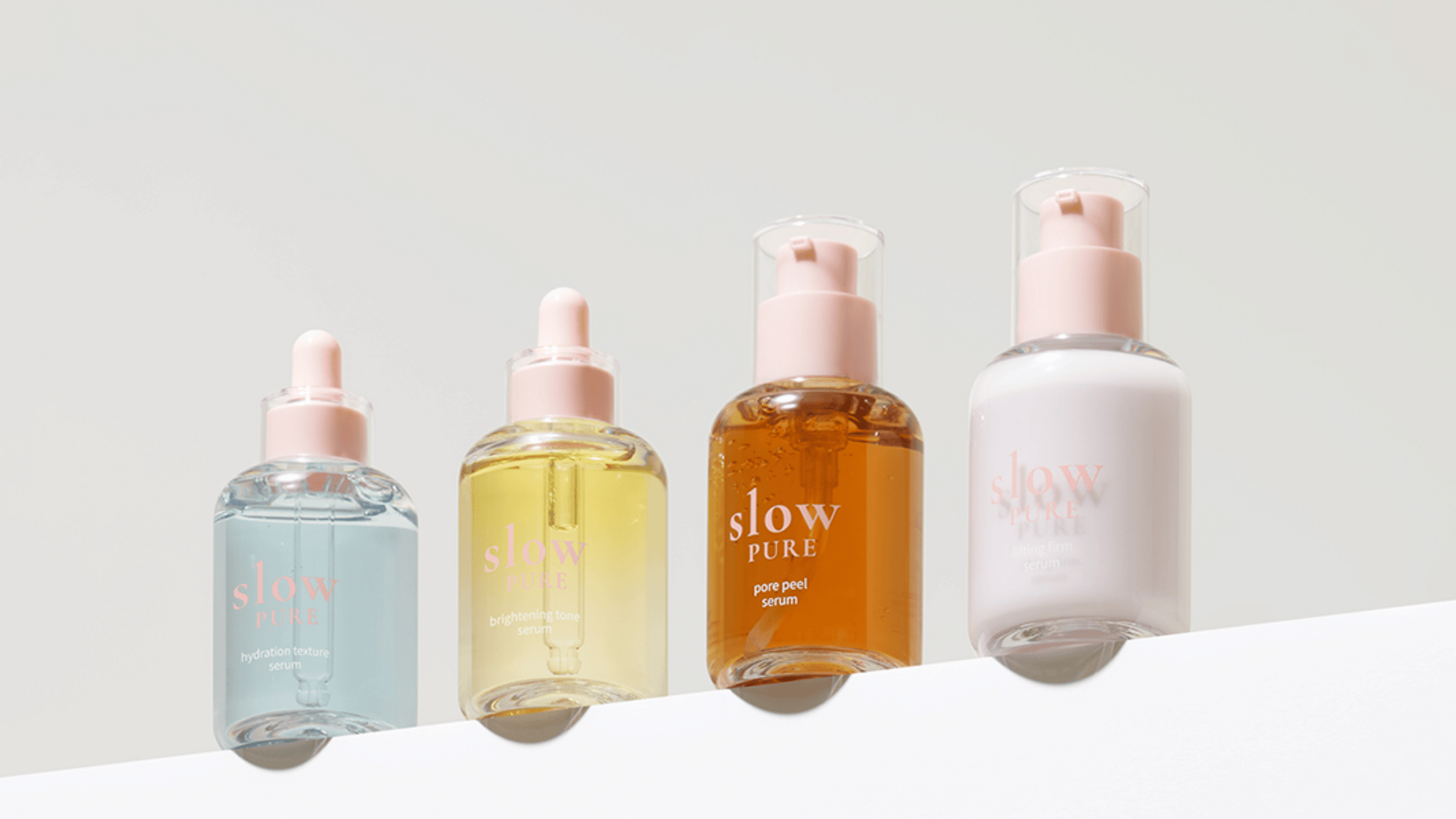 Fyra serum från Slow Pure i eleganta glasflaskor med rosa detaljer: Hydration Texture Serum, Brightening Tone Serum, Pore Peel Serum och Lifting Firm Serum.