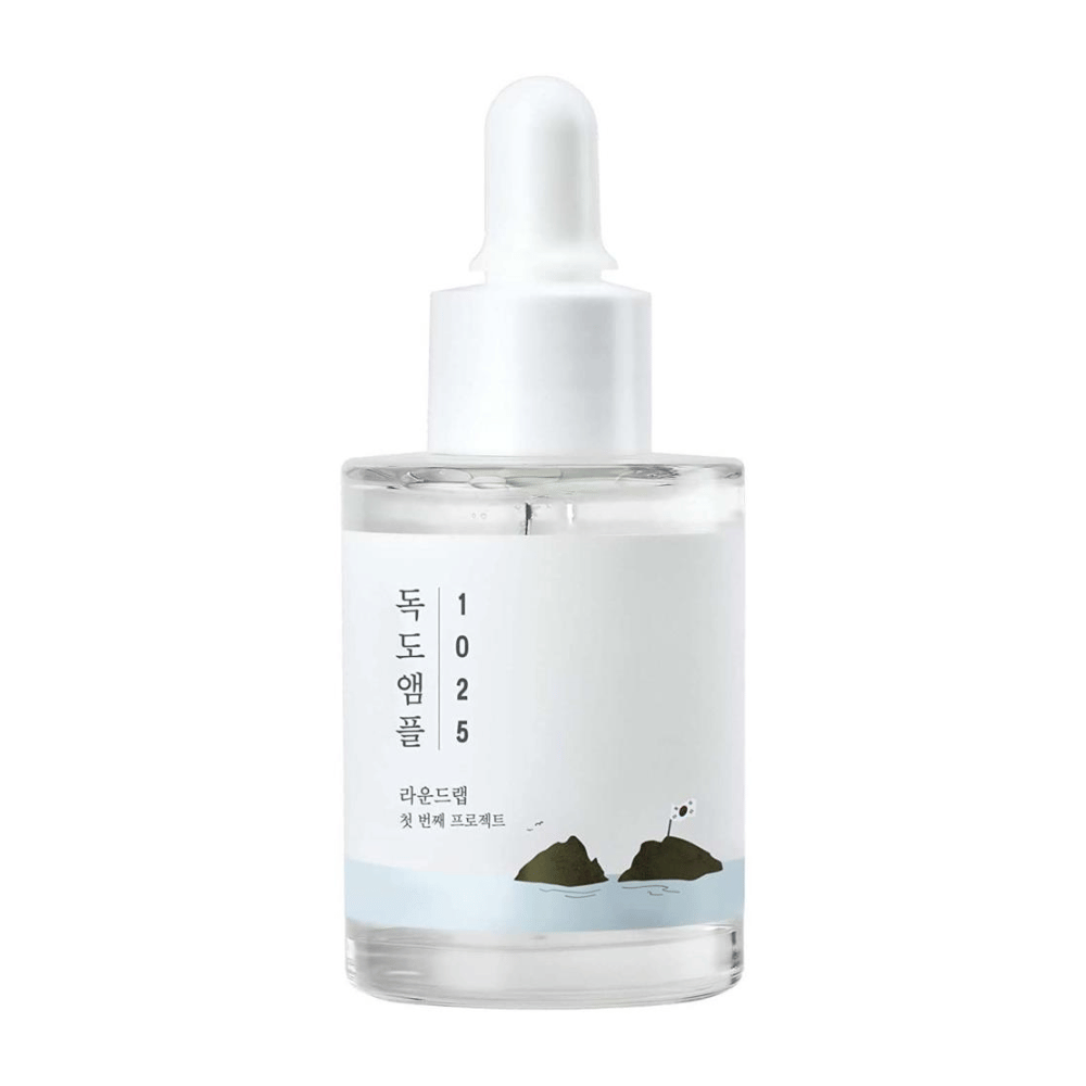 Priehľadná fľaša s pleťovým sérom 1025 Dokdo Ampoule, ozdobená minimalistickým námorným motívom, na bielom pozadí.
