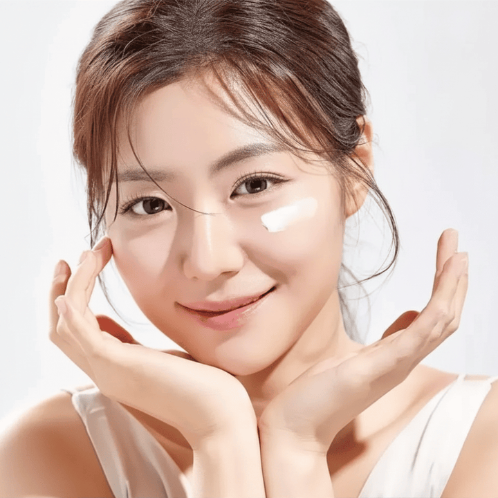 Žena si aplikuje Round Lab 1025 Dokdo Eye Cream pod oči pre hydratáciu, jas a rovnomernejší tón pleti