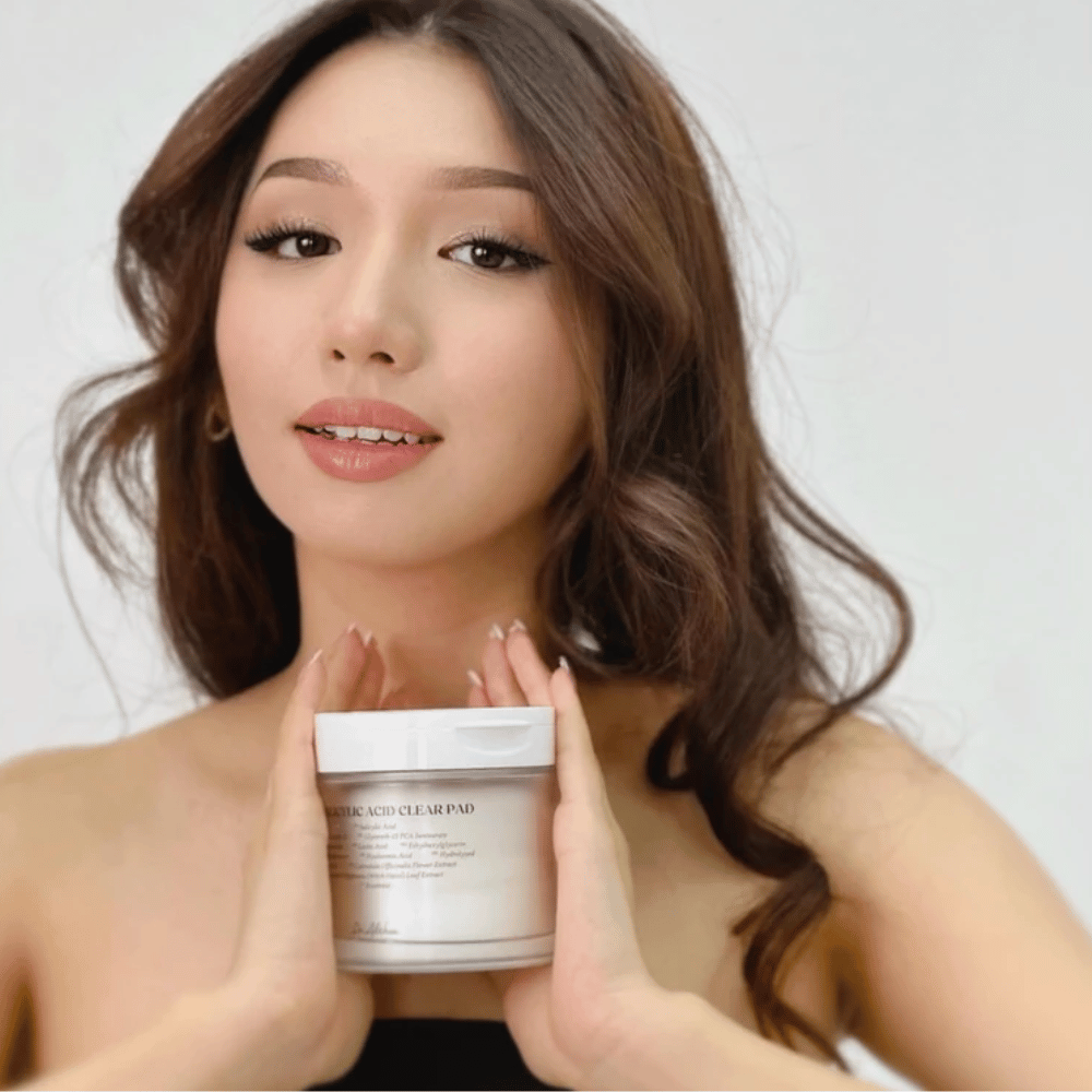 Model drží Dr. Althea 2% Salicylic Acid Clear Pad pred tvárou. Exfoliačné tonerové vankúšiky s kyselinou salicylovou, ktoré čistia póry, vyrovnávajú maz a poskytujú jasnejšiu pleť.