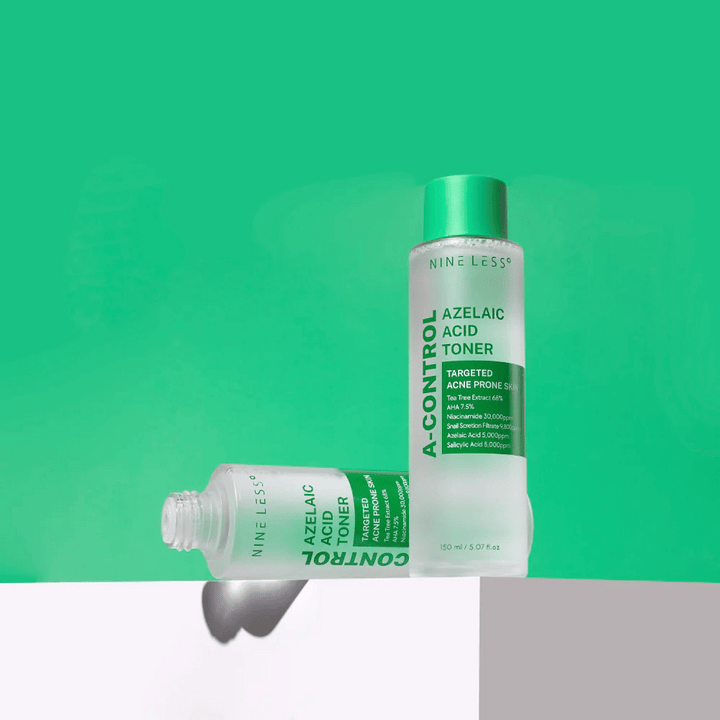 Dve fľaše Nine Less A-Control Azelaic Acid Toner umiestnené na zelenom pozadí, jedna stojaca a jedna ležiaca.