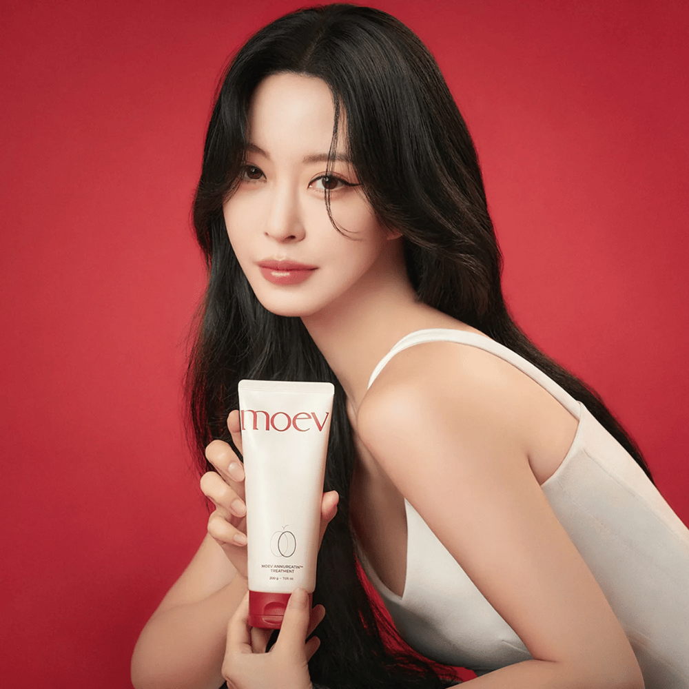 Žena s dlhými, lesklými vlasmi drží MOEV Annurcatin Treatment – kórejská starostlivosť o vlasy, ktorá poskytuje výživu, silu a lesk s prírodnými ingredienciami.