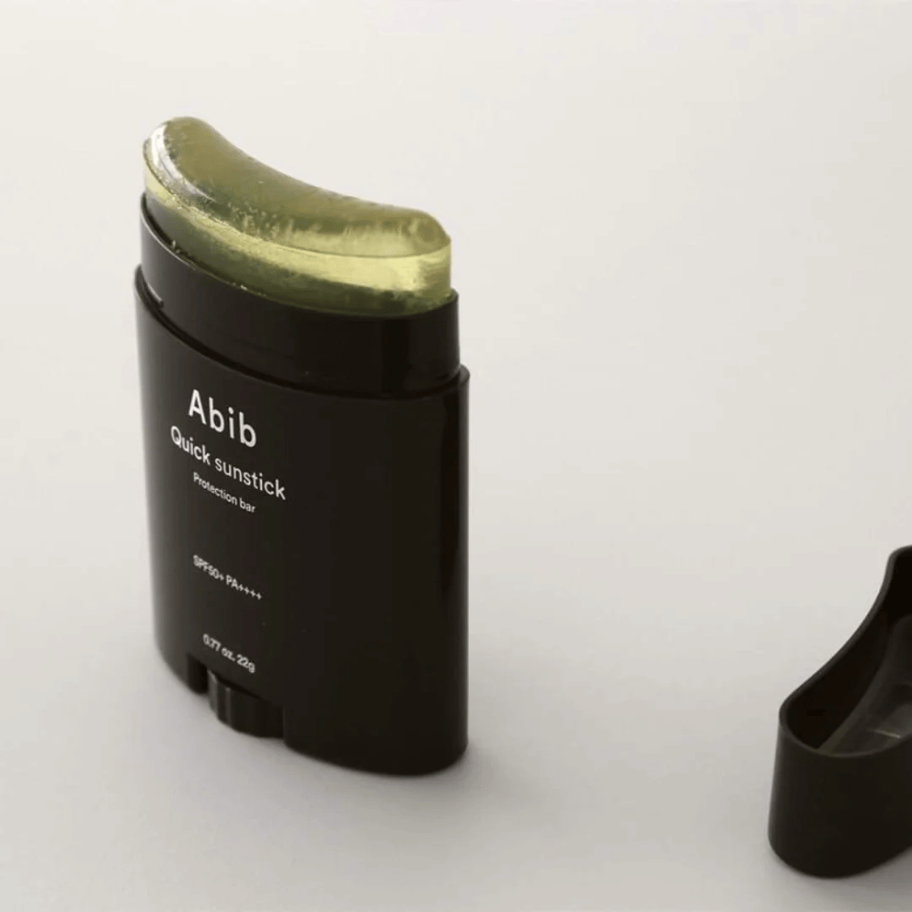 Čierna rúrka so zeleným vrchnákom, obsahujúca Quick Sunstick Protection Bar SPF50+ PA++++ 22g od Abib na ochranu pred slnkom.