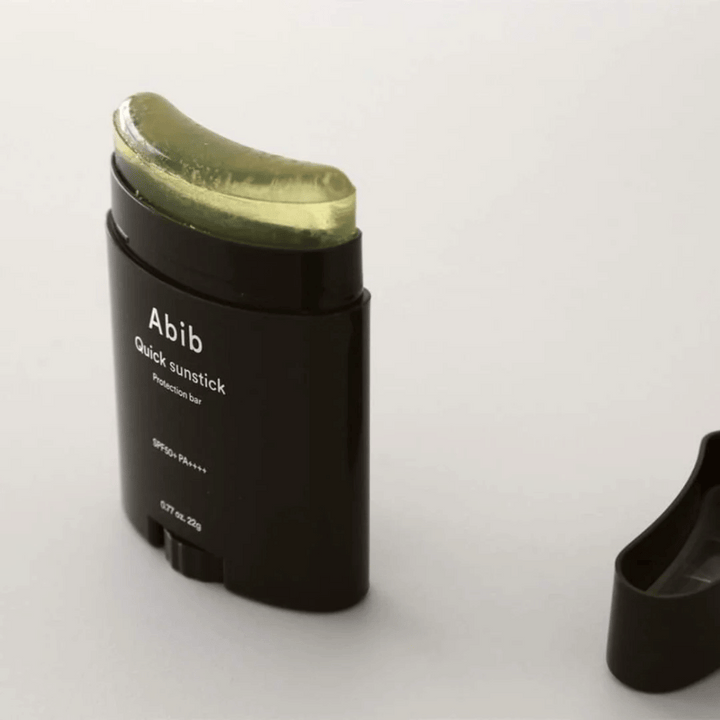 Čierna rúrka so zeleným vrchnákom, obsahujúca Quick Sunstick Protection Bar SPF50+ PA++++ 22g od Abib na ochranu pred slnkom.