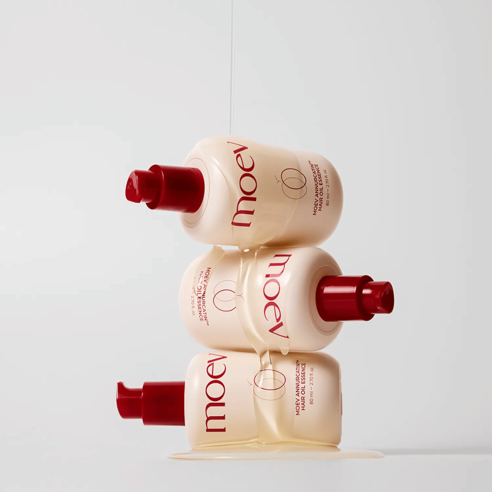 Tri fľaše MOEV Annurcatin Hair Oil Essence naskladané – výživný vlasový olej s Annurca-jablkom a biotínom, ktorý posilňuje, chráni a dodáva vlasom lesk a elasticitu.