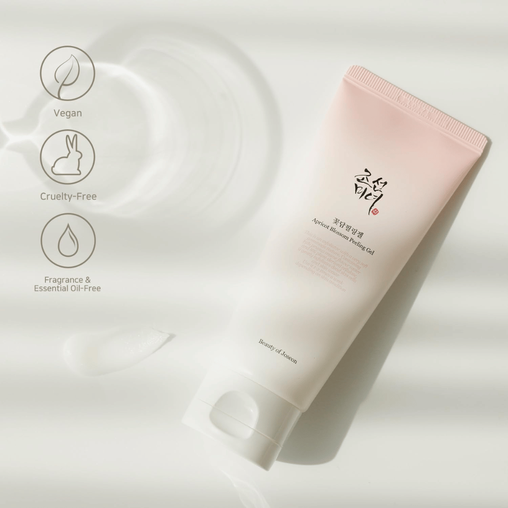 Tuba s Apricot Blossom Peeling Gel leží na odrazovej ploche s ikonami, ktoré označujú, že produkt je vegánsky, priateľský k zvieratám a bez vône a éterických olejov.