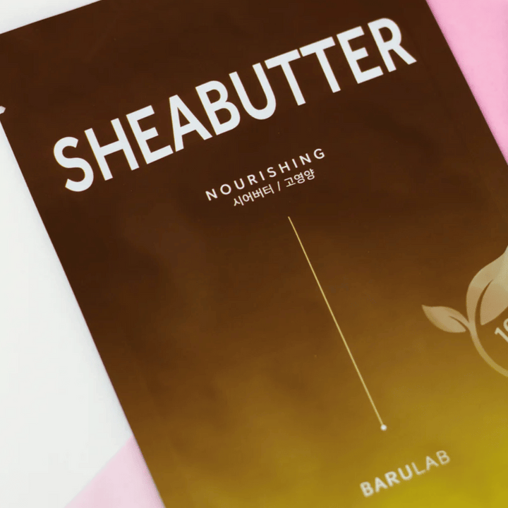 Detailný záber na balenie masky BARULAB "SHEABUTTER Nourishing". Produkt je označený ako "100% Vegan Product" a má farebný prechod z tmavo hnedej na svetlo hnedú.