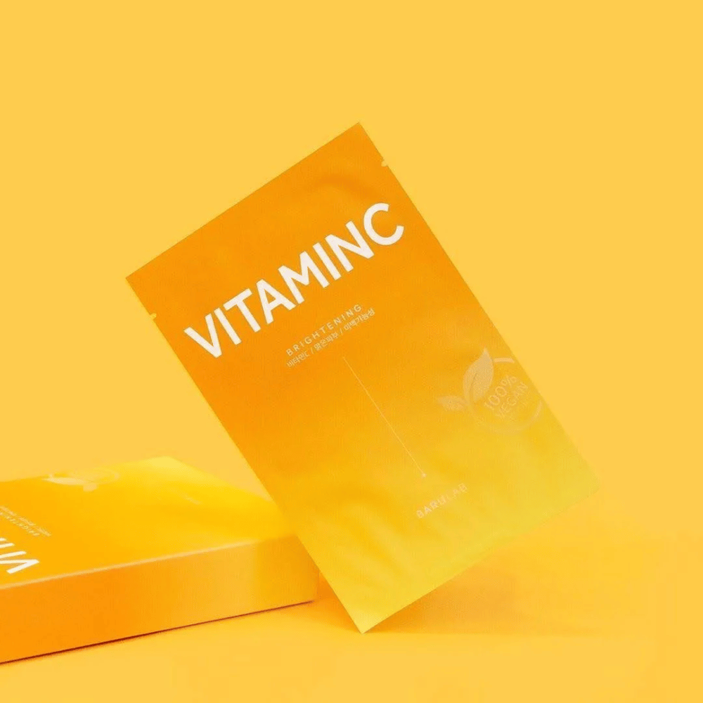 Kopa balení masiek BARULAB "VITAMINC Brightening", všetky označené ako "100% Vegan Product". Balenia majú farebný tón v rôznych odtieňoch oranžovej a žltej, umiestnené na jednotnom žltom pozadí.