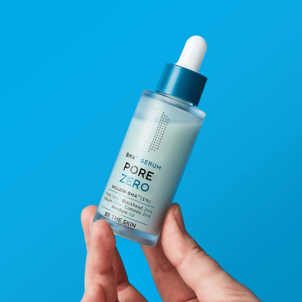 Be The Skin BHA+ Pore Zero Serum sa drží v ruke na modrom pozadí