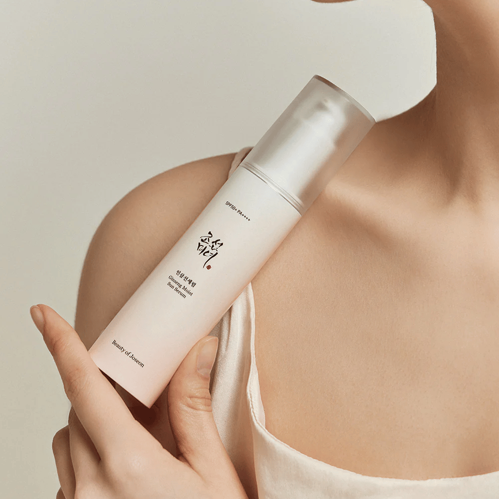 Žena, ktorá drží fľašu Beauty of Joseon's Ginseng Moist Sun Serum SPF 50+ PA++++, ktorá poskytuje ochranu SPF 50+ PA++++ a výhody starostlivosti o pleť.