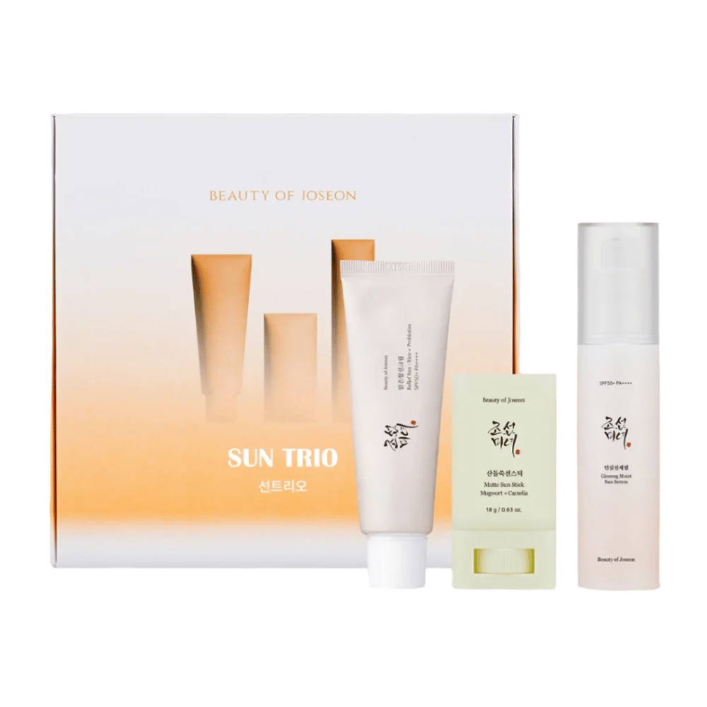 Beauty of Joseon - Sun Trio darčekové balenie s tromi opaľovacími produktmi: Relief Sun Rice + Probiotics, Matte Sun Stick Mugwort + Camellia a Ginseng Moist Sun Serum pred gradientovým balením v bielej a oranžovej farbe.