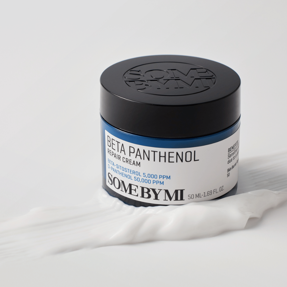 SOME BY MI Beta Panthenol Repair Cream v modrej nádobe umiestnenej na textúre krému – upokojujúci a hydratačný krém na pokožku.