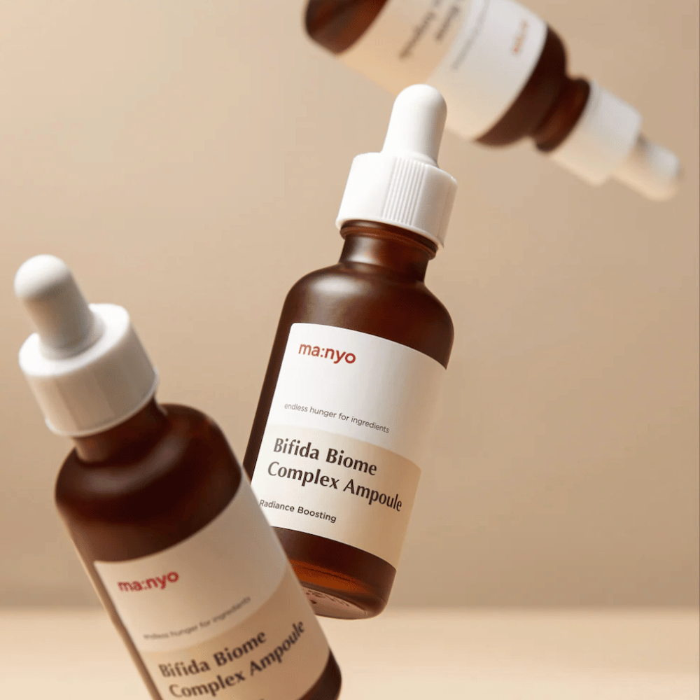 Produktový obrázok s viacerými levitujúcimi fľaštičkami ma:nyo Bifida Biome Complex Ampoule na béžovom pozadí, ktoré pôsobí moderne a minimalisticky.