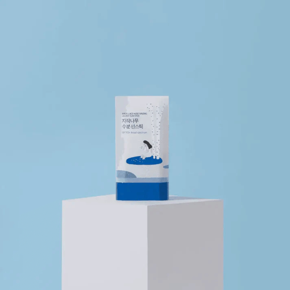 ROUND LAB Birch Juice Moisturizing Sun Stick SPF50+ stojí na podstavci na modrom pozadí – hydratačná ochrana pred slnkom v tyčinke