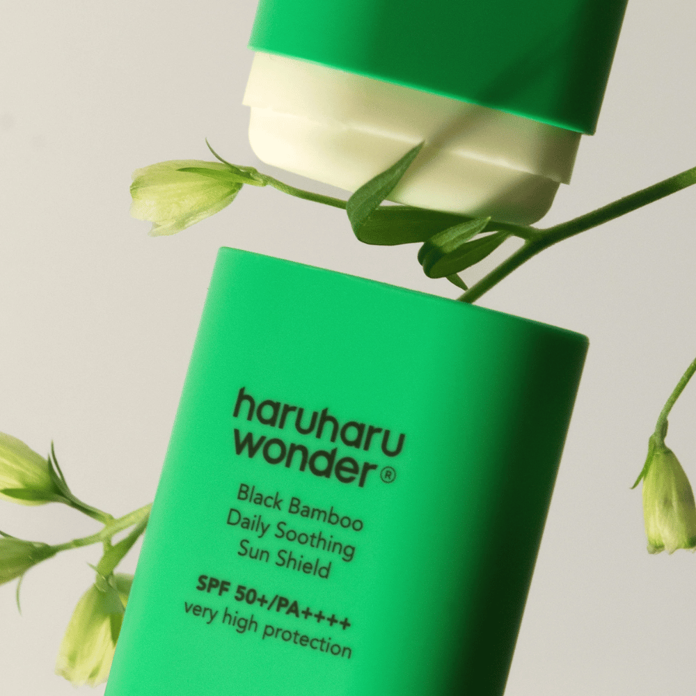 Detailný záber Haruharu Wonder Black Bamboo Daily Soothing Sun Shield – zelená ochrana proti slnku v tyčinkovom formáte s SPF 50+ PA++++, obklopená zelenými rastlinnými detailmi.