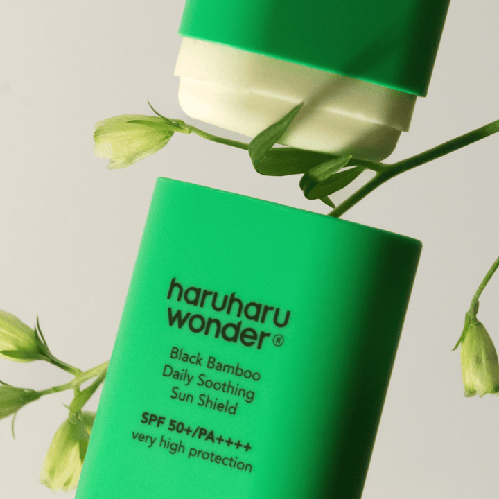 Detailný záber Haruharu Wonder Black Bamboo Daily Soothing Sun Shield – zelená ochrana proti slnku v tyčinkovom formáte s SPF 50+ PA++++, obklopená zelenými rastlinnými detailmi.