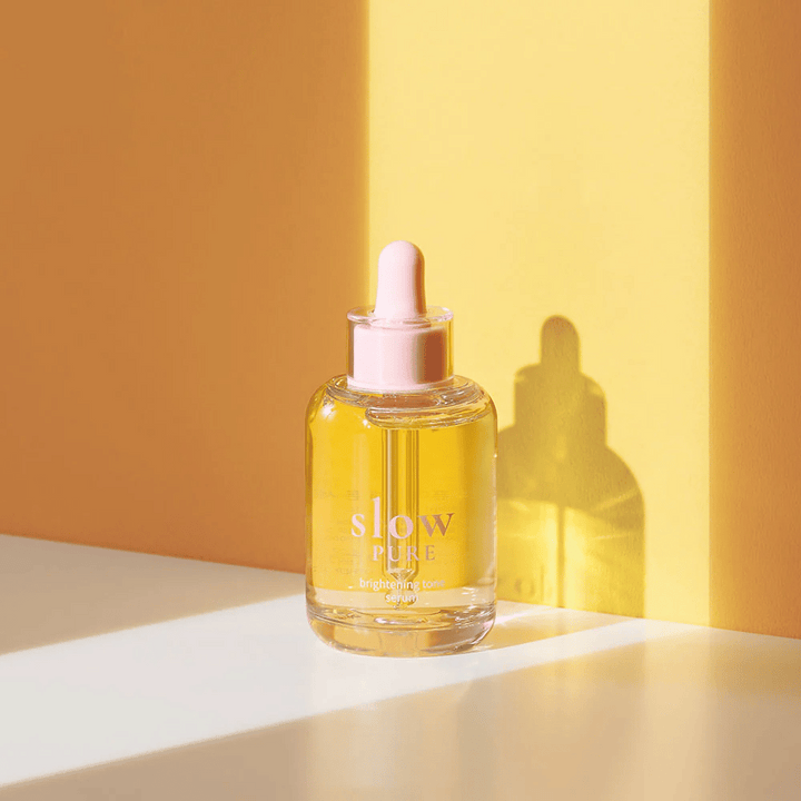 Slow Pure Brightening Tone Serum v slnečnom žltom svetle, symbolizuje žiarivosť a energiu pre pokožku.