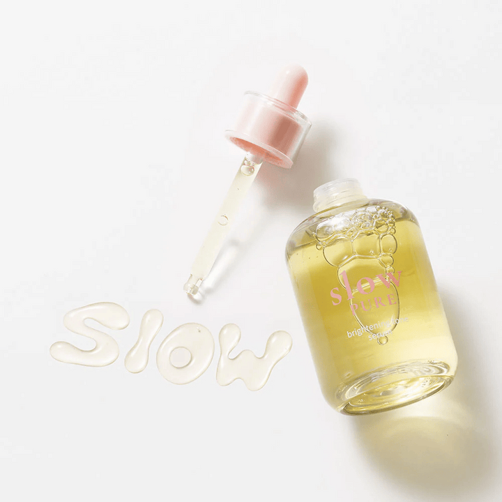 Slow Pure Brightening Tone Serum s otvorenou pipetou, text napísaný v sére na povrchu: "Slow".