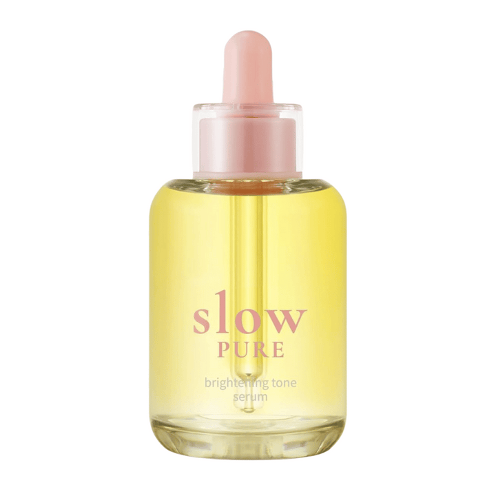 Slow Pure Brightening Tone Serum v čírej sklenenej fľaši s pipetou, naplnený žiarivým žltým sérom.