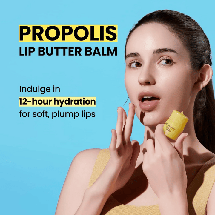 Žena aplikuje CNP Laboratory Propolis Lip Butter Balm, zvýraznená na modrom pozadí. Produkt sľubuje 12 hodín hydratácie pre jemné a plné pery, čo je zobrazené so žltou tubou, ktorú drží v ruke.