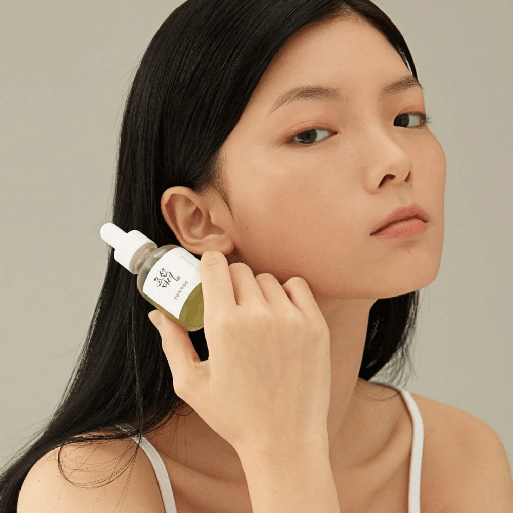Model drží Beauty of Joseon Calming Serum pri líci – zelený čaj a pantenol, ktoré posilňujú kožnú bariéru.