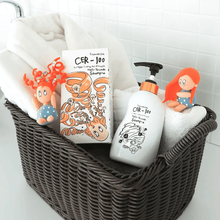 Prezentačný obrázok s Elizavecca CER-100 Shampoo a balením produktu umiestnenými v košíku spolu s uterákmi. Hravé figúrky z dizajnu obalu zdôrazňujú jedinečný a kreatívny štýl značky.