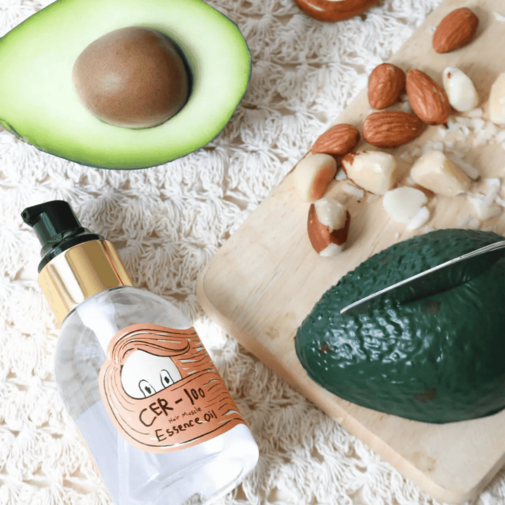 Elizavecca CER-100 Hair Muscle Essence Oil ingrediencie – detailný pohľad s avokádom a rastlinnými olejmi, ktorý ukazuje výživný vlasový olej, ktorý pomáha zmäkčovať a ošetrovať vlasy.