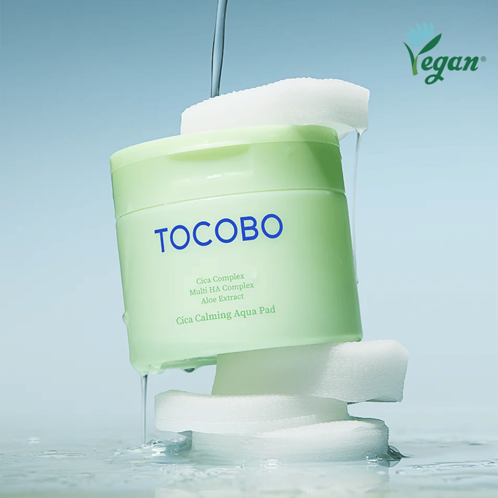 TOCOBO Cica Calming Aqua Pad umiestnený medzi toner pads s tečúcim essence. Symbol vegan zdôrazňuje vegánske zloženie produktu a jeho profil šetrný k pokožke.