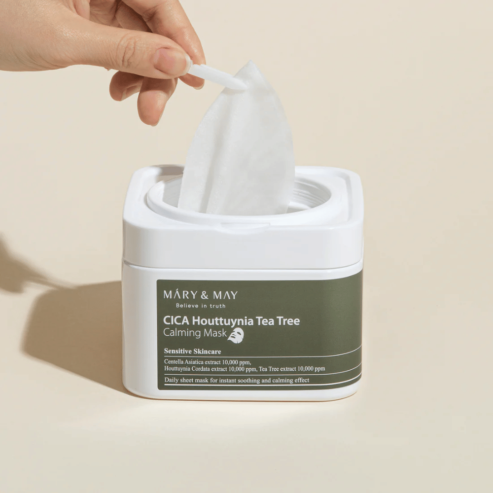 Ruka, ktorá vyťahuje pleťovú masku z nádoby Mary & May Cica Houttuynia Tea Tree Calming Mask – upokojujúca pleťová maska pre citlivú pokožku s extraktom Cica a Tea Tree.