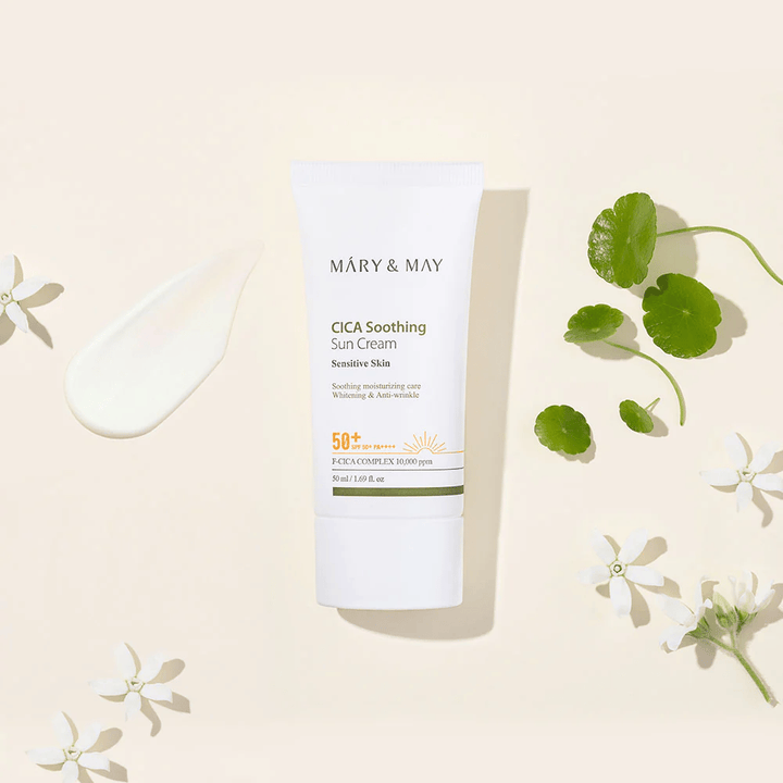 Mary&May CICA Soothing Sun Cream SPF50+ PA++++ prezentovaný spolu s krémovou textúrou, listami centelly a bielymi kvetmi. Obrázok zdôrazňuje upokojujúce vlastnosti produktu a zameranie na citlivú pokožku.