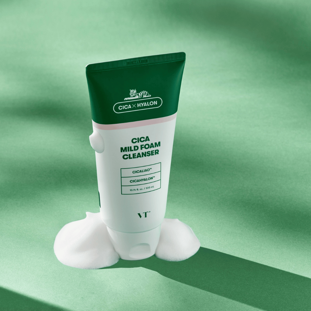 Tuba s VT Cica Mild Foam Cleanser stojaca na zelenom podklade s penou okolo základne. Produkt má zeleno-biely dizajn a je propagovaný s CICALIAO™ a CICAHYALON™.