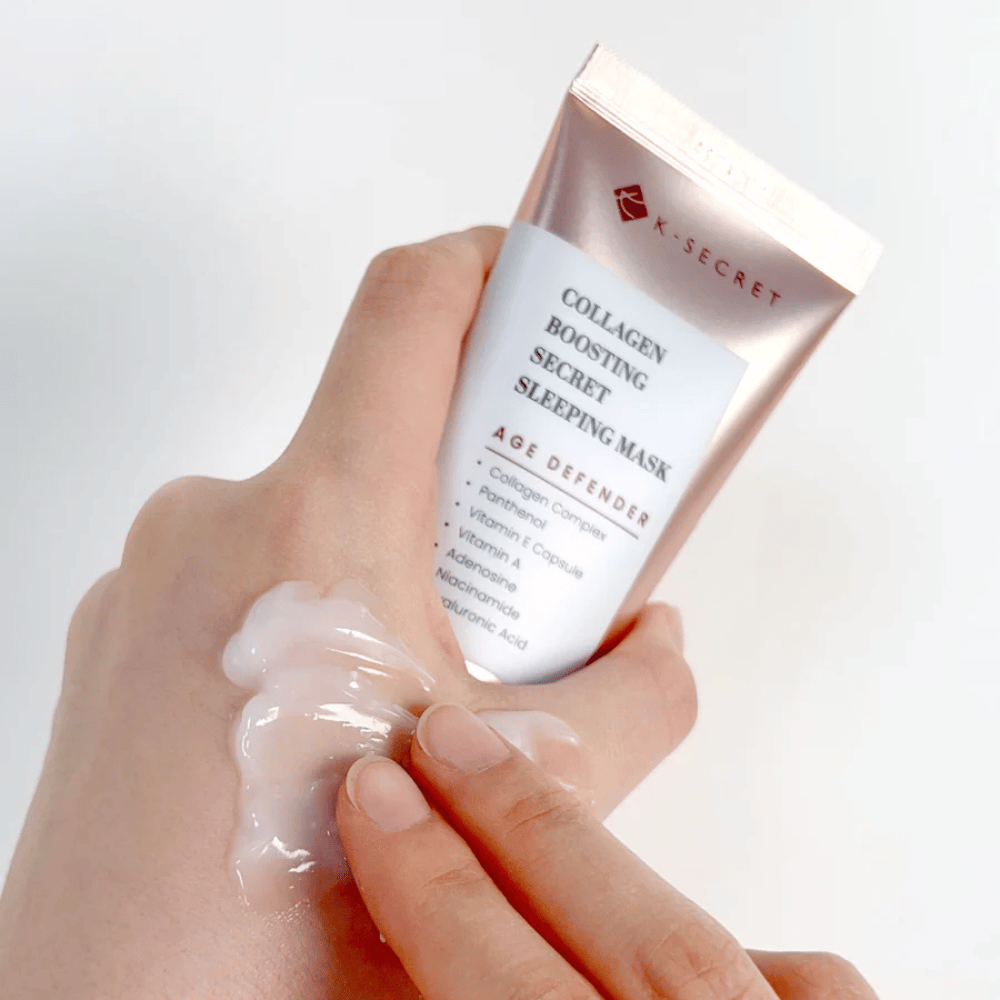 Ruka drží Collagen Boosting Secret Sleeping Mask, zatiaľ čo druhá aplikuje veľkorysé množstvo krému na vrch ruky – ukazuje konzistenciu a aplikáciu produktu.