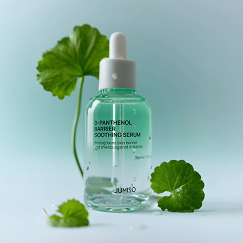 Jumiso D-Panthenol Barrier Soothing Serum v priehľadnej sklenenej fľaštičke s pipetou, umiestnené so zelenými listami v pozadí.