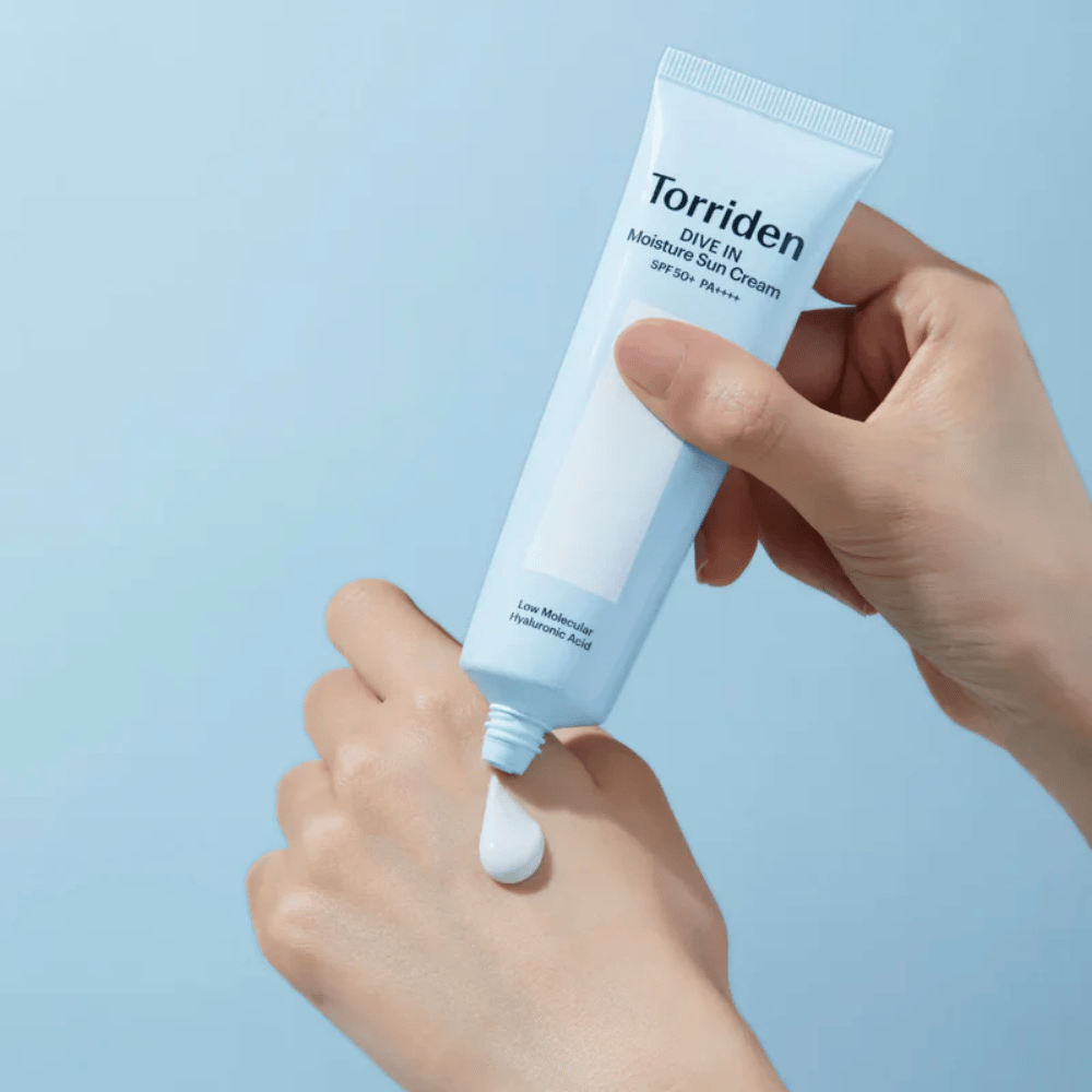 Torriden DIVE-IN Moisture Sun Cream SPF50+ PA++++ sa nanáša na ruku, aby ukázal ľahkú a krémovú konzistenciu hydratačného opaľovacieho krému.