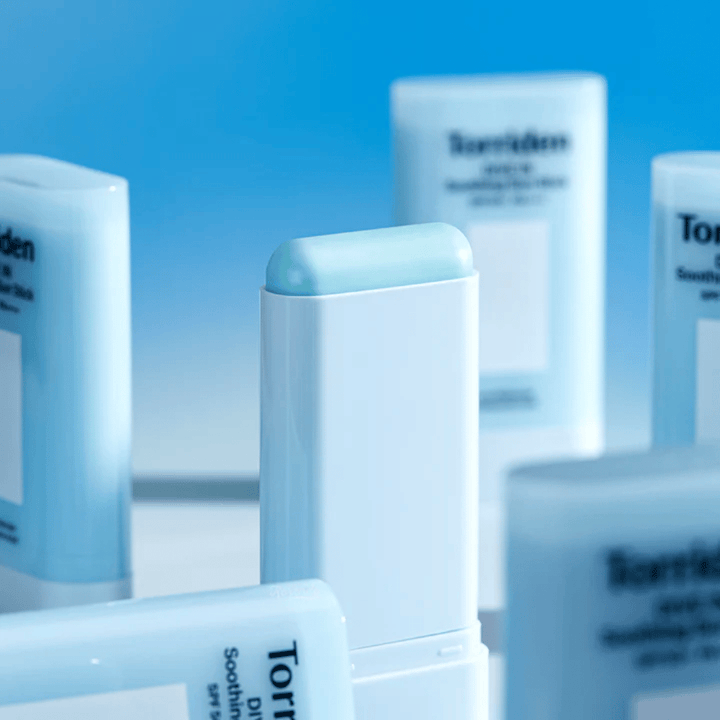 Detailný záber na Torriden DIVE IN Soothing Sun Stick, ktorý zobrazuje jemné zloženie opaľovacieho prípravku v tyčinke s viacerými produktmi v pozadí.