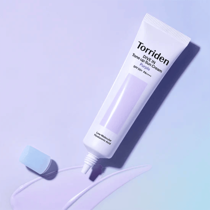Otvorená tuba Torriden DIVE IN Tone Up Sun Cream Purple s fialovo tónovanou textúrou opaľovacieho krému, ktorá ukazuje farebne korigujúce zloženie produktu.