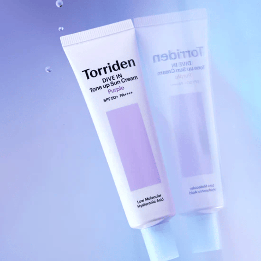 Torriden DIVE IN Tone Up Sun Cream Purple SPF50+ PA++++ odfotografovaný na jemnom fialovom pozadí, ktoré zvýrazňuje svetlo odrážajúci dizajn produktu.