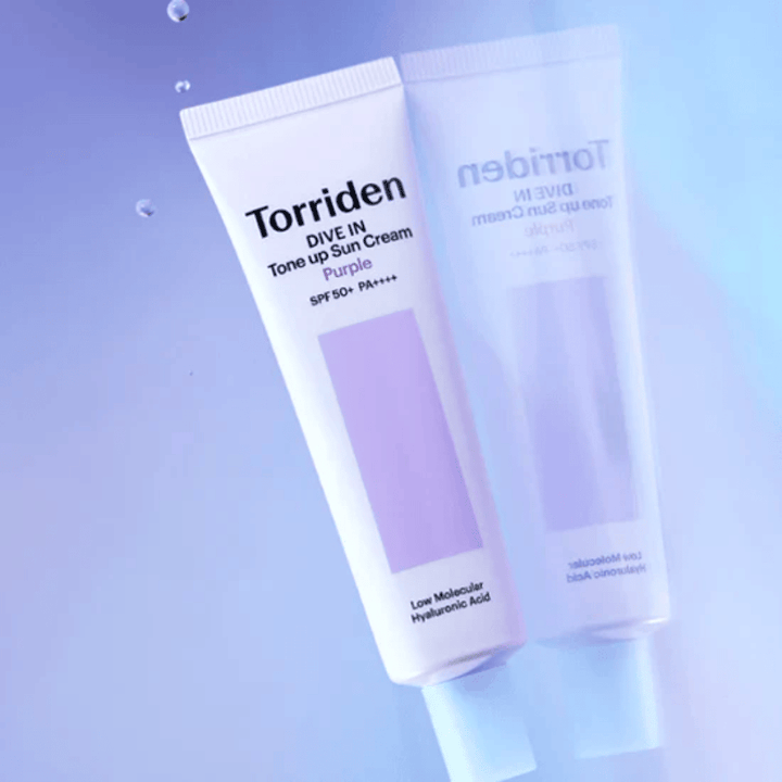 Torriden DIVE IN Tone Up Sun Cream Purple SPF50+ PA++++ odfotografovaný na jemnom fialovom pozadí, ktoré zvýrazňuje svetlo odrážajúci dizajn produktu.