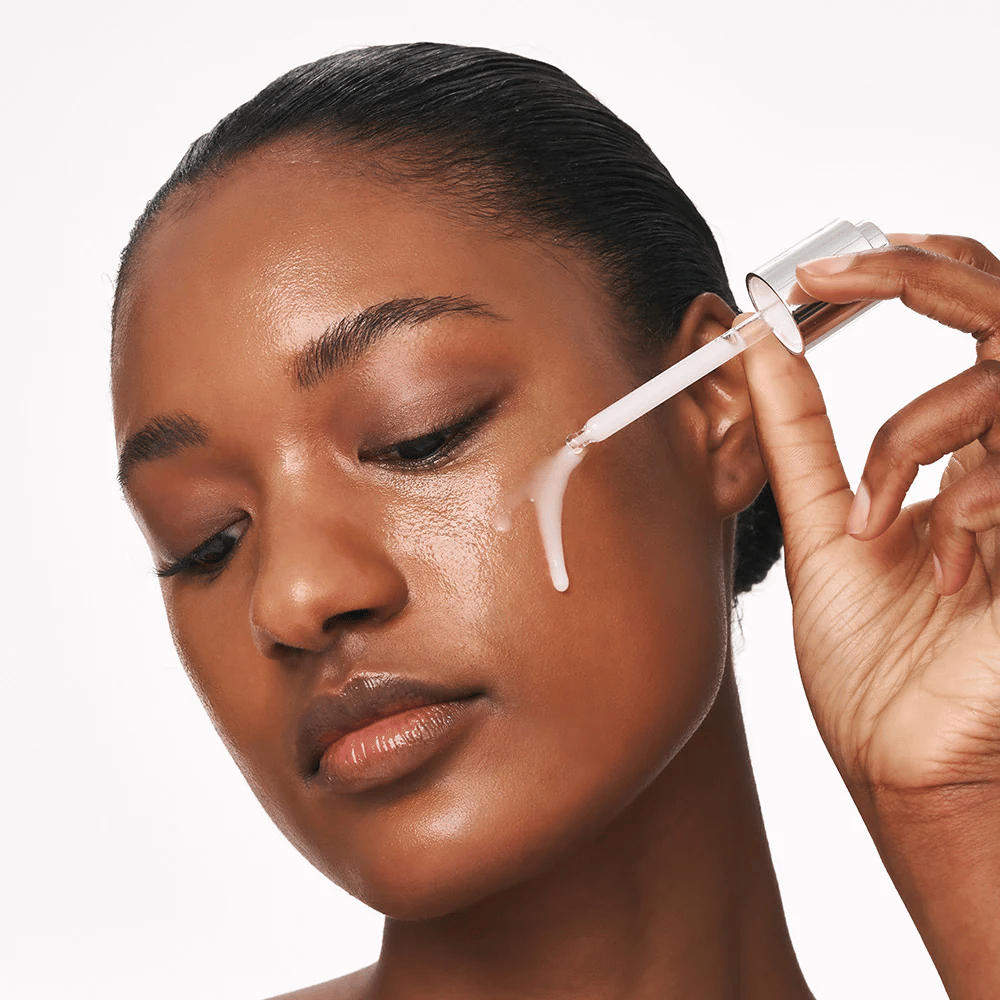 Osoba aplikuje Deep Collagen Power Boosting Cream in Serum na líce pomocou pipety. Sérum poskytuje pevnejšiu, hydratovanú pleť so žiarou.