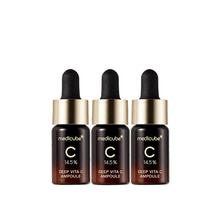 Tri fľaše Medicube Deep Vita C Ampoule, s 14,5 % vitamínu C, usporiadané v rade. Fľaše majú elegantný dizajn s tmavohnedým základom a zlatým uzáverom. Perfektné pre svetlejší tón pleti a rovnomernejšiu textúru pokožky.