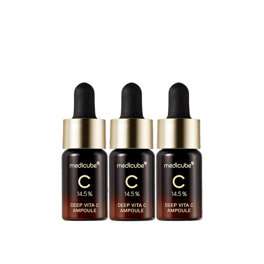 Tri fľaše Medicube Deep Vita C Ampoule, s 14,5 % vitamínu C, usporiadané v rade. Fľaše majú elegantný dizajn s tmavohnedým základom a zlatým uzáverom. Perfektné pre svetlejší tón pleti a rovnomernejšiu textúru pokožky.