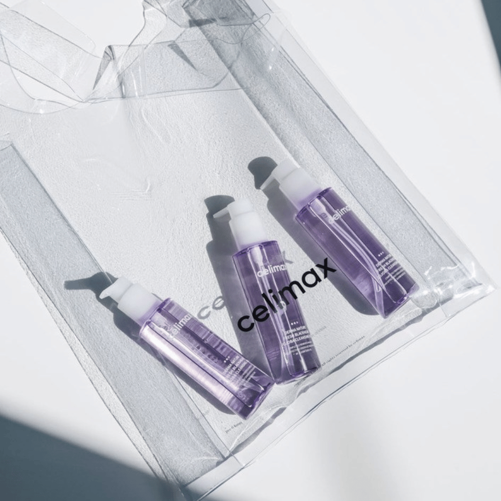 Tri fľaše Celimax Derma Nature Fresh Blackhead Jojoba Cleansing Oil vo fialovom balení, umiestnené v priehľadnej taške s logom 'celimax'.