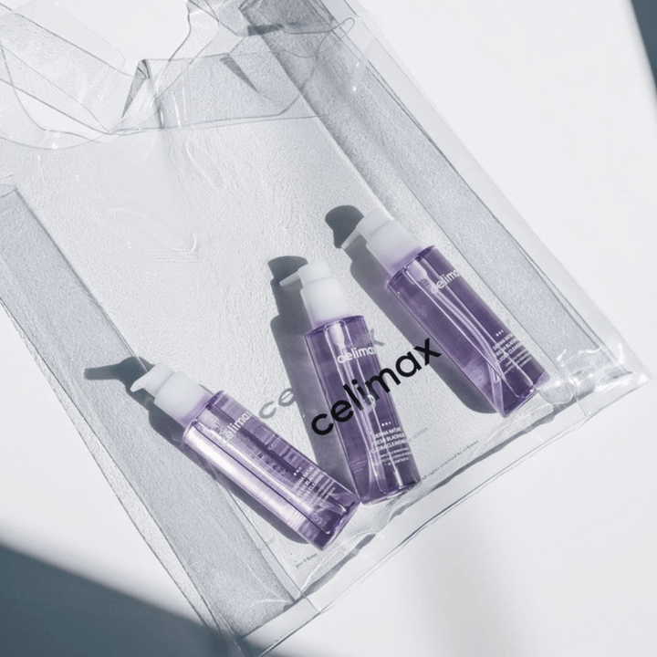 Tri fľaše Celimax Derma Nature Fresh Blackhead Jojoba Cleansing Oil vo fialovom balení, umiestnené v priehľadnej taške s logom 'celimax'.