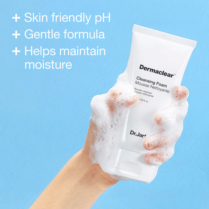 Ruka pokrytá penou drží Dr.Jart+ Dermaclear Cleansing Foam proti modrému pozadiu, s textom, ktorý zdôrazňuje pH priateľské k pokožke, jemnú formulu a hydratačné vlastnosti.