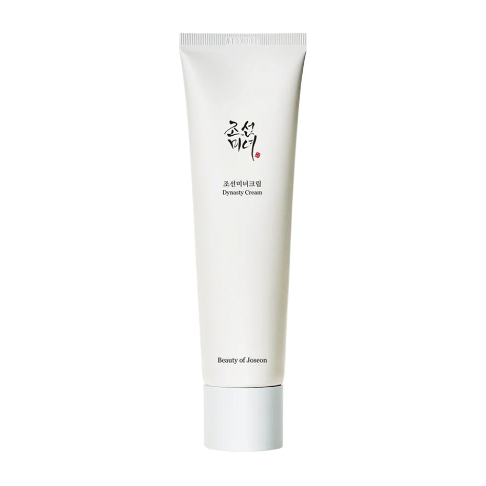 Obrázok zobrazuje tubu "Beauty of Joseon Dynasty Cream". Štíhla, biela tuba má minimalistické dizajnové prvky, vrátane elegantného čierneho a červeného textu. Tento produkt starostlivosti o pleť sľubuje vyživovať a revitalizovať pleť, čo odráža historické kozmetické tajomstvá z dynastie Joseon.