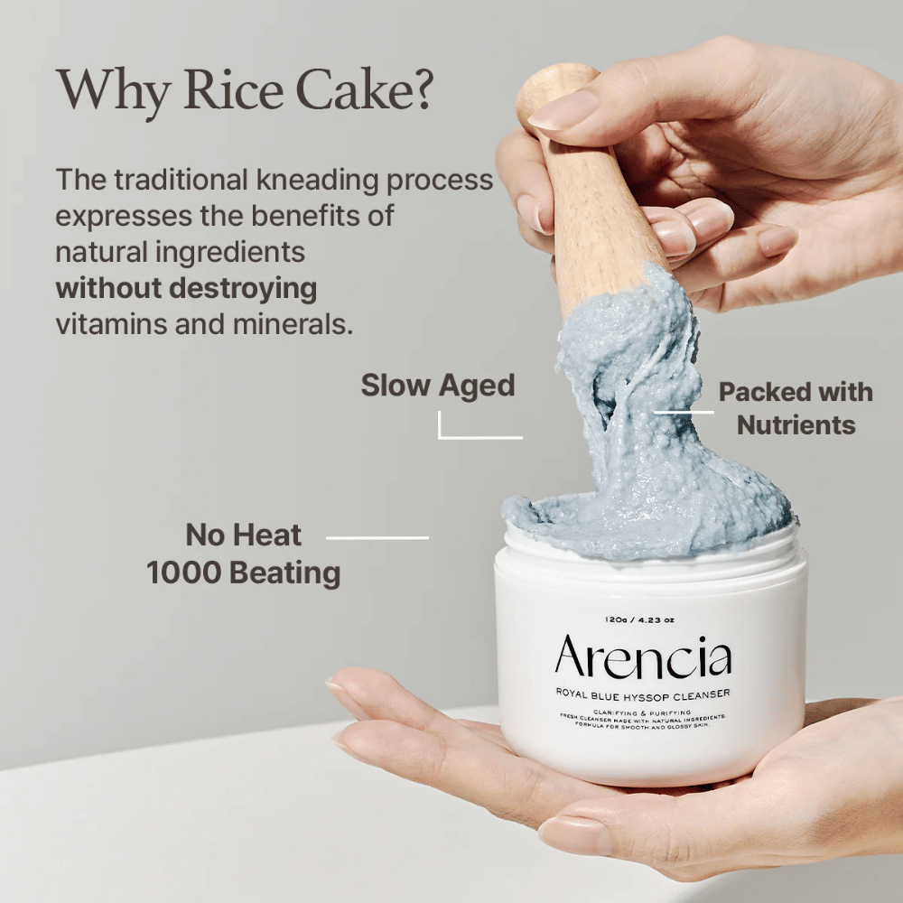 Ruka držiaca čistiacu nádobu "Arencia Royal Blue Hyssop Cleanser" s drevenou lyžicou, ktorá naberá modrú, mochi-podobnú čistiacu pastu. Text na obrázku opisuje výhody procesu ryžového cesta, ako sú "Bez tepla", "1000 úderov", "Pomaly zrejúce" a "Nabitý živinami".