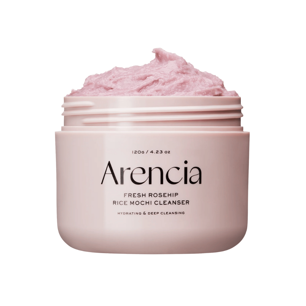 Záber na ružovú nádobu s Arencia Royal Rosehip Cleanser, naplnenú ružovým čistiacim krémom s textúrou podobnou šľahanému mochi. Text na nádobe ukazuje, že produkt hydratuje a čistí do hĺbky.