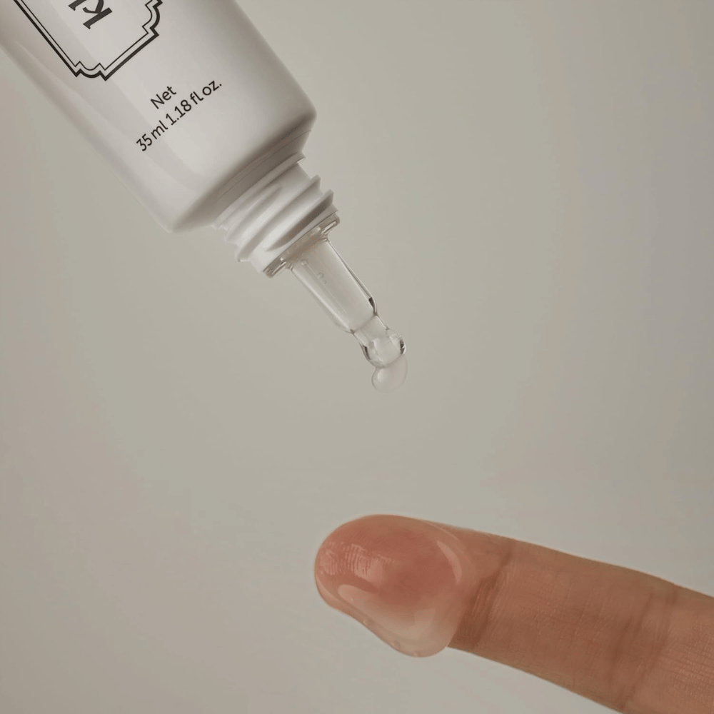 Detailný záber, na ktorom sa číry, ľahký gél nanáša z úzkeho hrotu na prst. Obrázok ilustruje transparentnú, gélovú konzistenciu produktu a presnú aplikáciu v okolí očí.