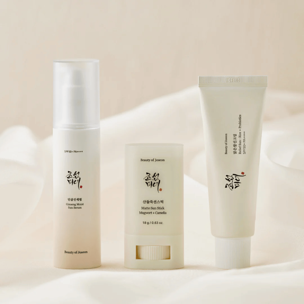 Tri opaľovacie produkty od Beauty of Joseon – Ginseng Moist Sun Serum, Matte Sun Stick a Relief Sun Rice + Probiotics – sú zoradené na krémovom plátne s jemným svetlom.